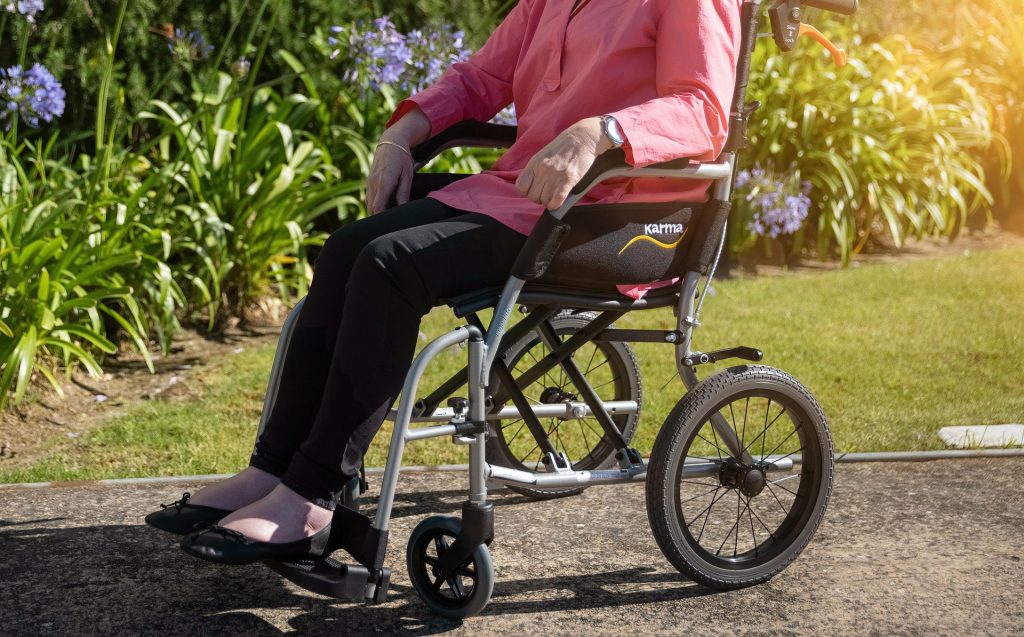Foto de uma mulher em uma cadeira de rodas, com plantas ao fundo. Imagem ilustrativa para o texto seguro auto para deficiente físico.