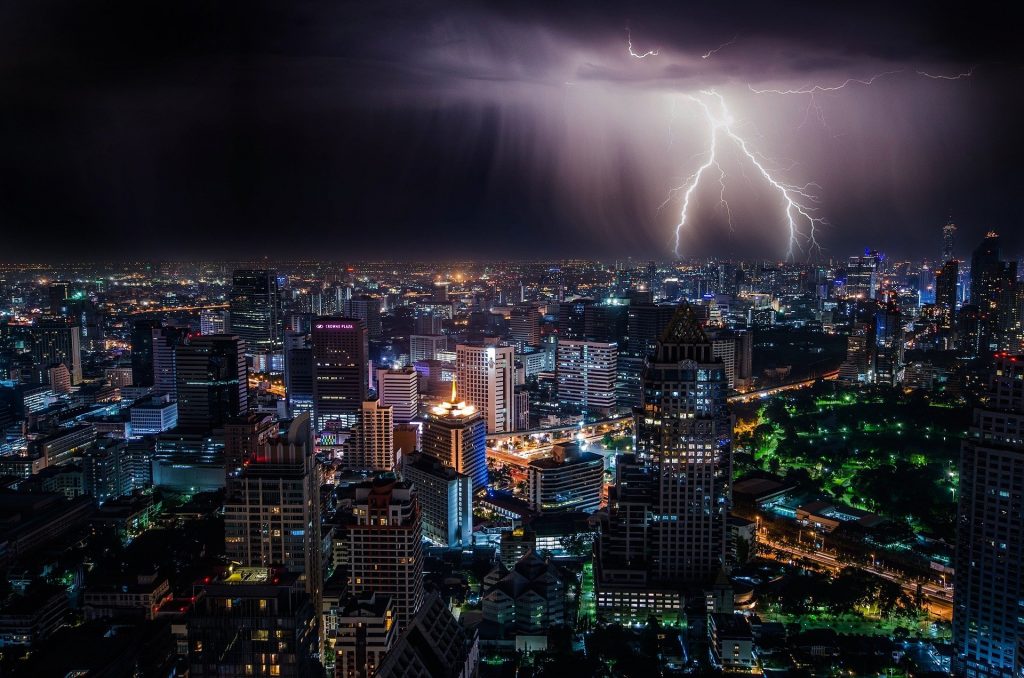 Foto de uma cidade e uma tempestade com raios caindo. Imagem ilustrativa para o texto seguro contra intempéries.